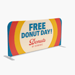 An event barrier promoting a donut shop, featuring stylised text and a logo. 