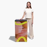 A person standing behind a trade show display counter promoting a wellness brand.