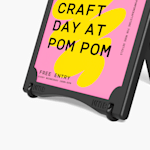 A close-up of a black water-fillable A-frame promoting a craft business, with one pair of wheels attached.