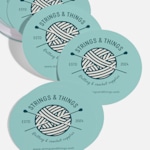 Circle name cards promoting a crochet business, displayed on a counter.