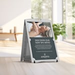 A white, water fillable A-frame promoting a spa's new services, displayed indoors.