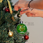 A person hanging up a Christmas bauble featuring a festive quote. An arrow points to the clear acrylic material.