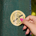 A person placing a circle sticker for a natural food business on an iron surface.