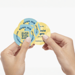 A person holding three circle business cards with QR codes in the design.