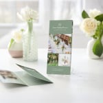Several tri-fold menus for a wedding planning company, displayed in a clear plastic holder.