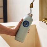 A waterproof label on the side of a water bottle getting splashed as the bottle is refilled.