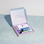 A square mailer box filled with goodies from a travel agency.