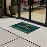 A close up of a logo floor mat on a tiled floor.