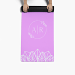 A pair of hands unrolling a custom yoga mat printed with a monogram.