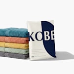A custom poly mailer shown next to a stack of towels promoting home goods.