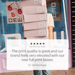 A person holding a stack of full-print mailer boxes in front of a store. A featured customer quote showcases the print quality and elevated brand look.