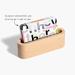 Una pila de tarjetas de visita con barniz UV y esquinas redondeadas colocadas sobre un soporte de madera.