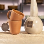 Una etiqueta colgante atada con un cordón a una taza y a un recipiente de cerámica.