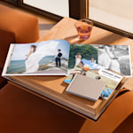 Libros de fotos de distintos tamaños expuestos en una mesa de salón. Un fotolibro abierto muestra fotos de boda.