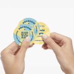 A person holding three circle business cards with QR codes in the design.