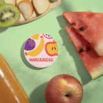 A stack of circle business cards for a juice company. The circle cards are sitting next to fresh fruits and a bottle of juice.
