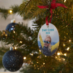 Un adorno personalizado en un árbol de Navidad con una foto de una niña con gafas de sol.