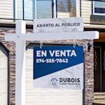 Una imagen de cerca de una placa de información superior de un open house en un poste colonial blanco frente a una casa.