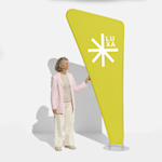 A bright yellow triangle zipper banner with a woman standing next to it for scale.