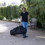 Un hombre empujando una carpa plegable en su estuche, en un ambiente al aire libre.