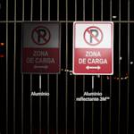 2 letreros para estacionamiento se muestran colgados de una cerca en la noche.