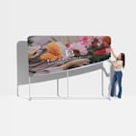 Una mujer colgando la tela sobre el marco de aluminio de un backing publicitario de tubos.