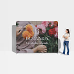 Se muestra a una mujer parada junto a un backing publicitario de tubos con flores como referencia de escala.