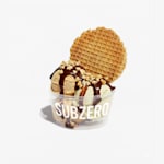 Un vaso plástico para helado con varias bolas de helado, nueces y topping de waffle.