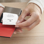 Nainen ottaa kortin mustasta nahkaisesta pystysuorasta käyntikorttikotelosta.