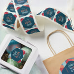 Un rouleau d’étiquettes d’emballage personnalisées pour une entreprise de décoration intérieure, dont quelques-unes ont été collées sur des sacs et des boîtes.