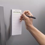 Un bloc-notes personnalisé pour les listes de courses, affiché sur un réfrigérateur.