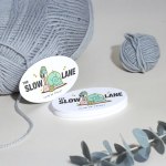 Une pile de cartes d’affaires ovales pour un club de tricot, avec du fil et des plantes en arrière-plan.