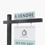 Un ajout annonçant un bien à la vente, placé en haut d’un poteau potence noir, auquel est suspendue une pancarte immobilière d’extérieur.