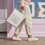 Un sac en papier kraft blanc conçu pour une boutique de vêtements vintage, présenté avec un autocollant à code QR placé en haut à gauche.
