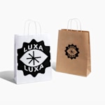 Un sac en papier kraft marron et un sac en papier kraft blanc provenant d’une entreprise de superaliments, affichant le logo de celle-ci en plusieurs styles sur chaque sac.