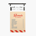 Un tableau de menu affichant le menu d’une boutique de beignes avec les prix. Les pièces d’assemblage incluses sont présentées au-dessus du tableau de menu.