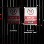 Deux pancartes de stationnement accrochées à une clôture visibles de nuit.