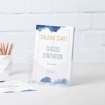 Un présentoir en plastique A4 contenant des flyers pour une galerie d’art est posé sur un bureau, à côté d’un pot à crayons.