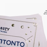 Primo piano di un biglietto da visita raffigurante un logo e una scritta metallizzati color oro in rilievo.
