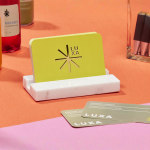 Visittkort med uthevet skrift for en restaurant eller matrelatert bedrift plassert i en visittkortholder av marmor.