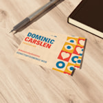 En bunke visittkort av lin for en donut-butikk vises på en benkeplate av tre ved en notisbok og en kulepenn