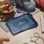 Visittkort med UV-spot finish for en strikkebedrift på et skrivebord.