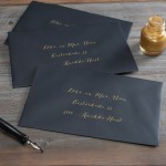Zwarte enveloppen, geadresseerd met goudkleurige inkt.