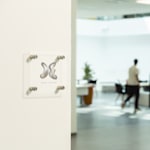 vierkant bord van acryl met logo op een witte deur in een kantooromgeving