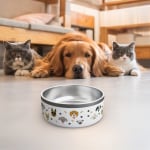 Een witte bedrukte hondenvoerbak bedrukt met verschillende hondenontwerpen en hondenbotten en pootafdrukken. Twee katten en een hond kijken van achteren naar de bak.