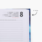 Een close-up van een geopende hardcover agenda. Er staat een notitie bij die aangeeft dat de tekst op de pagina's in 8 talen wordt weergegeven.
