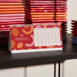 Een rechthoekige bureaukalender met reclame voor een chocoladebedrijf.