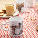 Twee mokken met hartvormig oor op een ontbijttafel.