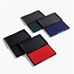 Vier inktstempelkussens met open deksels, die de kleuren van de kussens in zwart, groen, blauw en rood tonen.