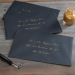 Envelopes pretos endereçados a tinta dourada.